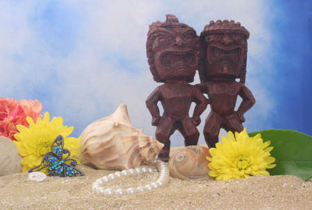 Tiki Statue With Flowers and Sea Shells on Blue Sky Backgroundの写真素材