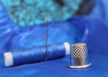 Blue Thread with needle and thimble on blue prom dress