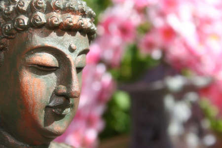 Buddha Statue in Outdoor Garden With Blurred Cherry Blossoms in Background