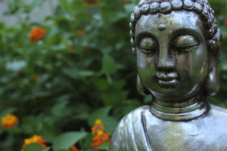 Buddha Statue in Garden with green plants in background