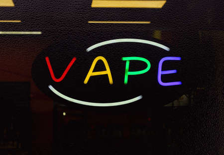 Neon Vape Sign in Rainy Smoke Shop Window, Focus on Neon Lettersの写真素材