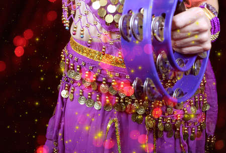Belly Dancer wearing purple dance costume close up with colorful bokehの写真素材