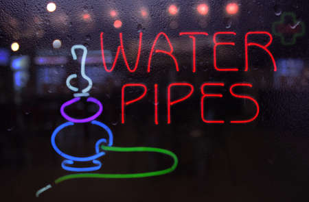 Vintage Neon Water Pipe Sign in Rainy Windowの写真素材