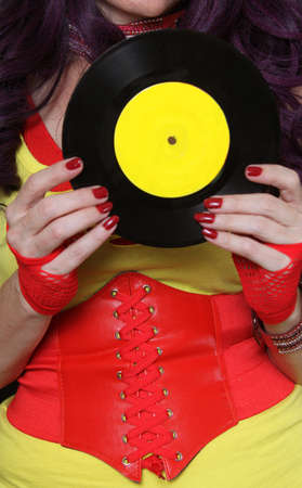 Woman in 1980s yellow clothing holding 45rpm record. Record label painted with yellow paint