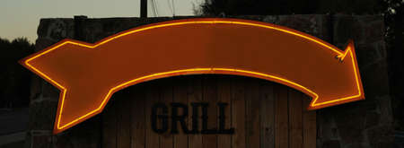 Vintage Neon Arrow Sign at Sunset Pointing to Restaurantの写真素材
