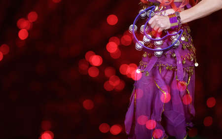 Belly Dancer wearing purple dance costume close up with colorful bokeh