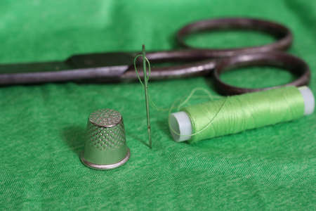Spool of Green Thread, Thimble and Needle on Green Fabricの写真素材