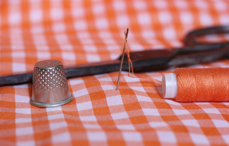 Orange and White Checkered Fabric With Thimble and Spool of Orange Threadの写真素材