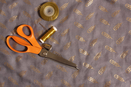 Spool of Metallic Gold Thread on Gray and Gold Fabric