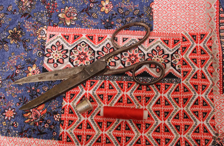 Red Thread and Thimble on Colorful Vintage Fabric With Needle