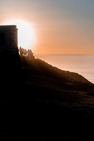 Silhouette of a group of people watching the sunset with sun rays through them.