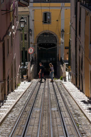 Young couple crossing the tram lines in front of a tunnel.
