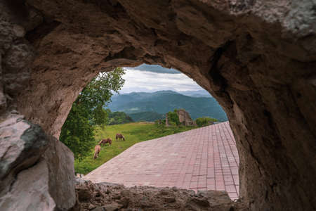 Framed view from rocky window of 3 horses eating grass.の写真素材