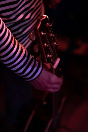 Man grabbing a guitar under neon lightsの写真素材