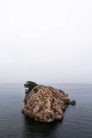 Lonely rock in the middle of the sea with a misty vibeの写真素材