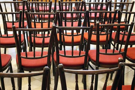 Rear view of many wooden chairs with red fabricの写真素材