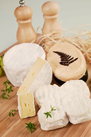 Luxurious cheese variation arranged on wooden board with fresh herbs.の写真素材
