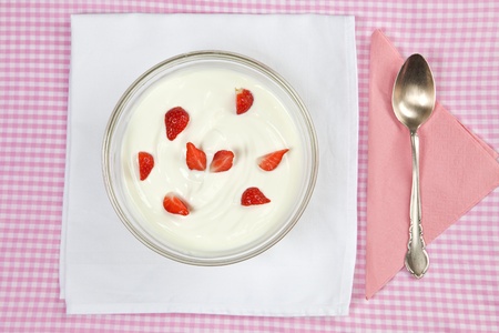 Bowl with fresh strawberries in yogurt with silver spoon.の写真素材
