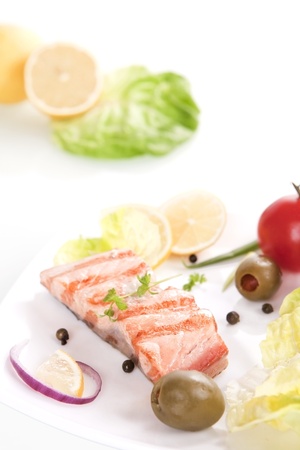 Grilled salmon steak piece with olives, salad, onion and lemon.の写真素材