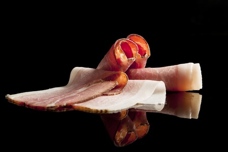 Bacon and ham slices isolated on black background.の写真素材