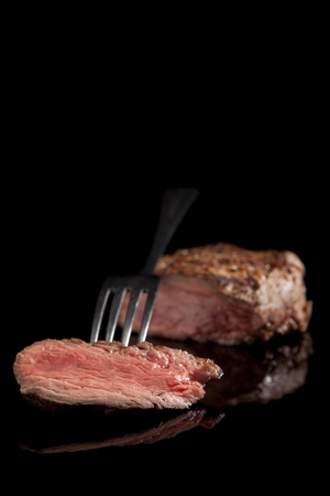 delicious beef steak with fork on black backgroundの写真素材