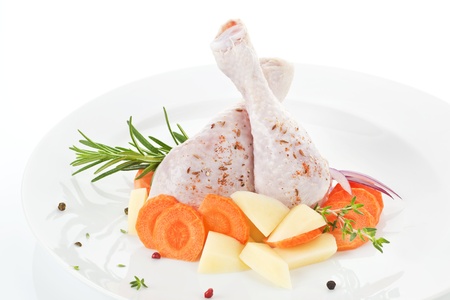 Two chicken legs with fresh vegetables and herbs on white plate. の写真素材