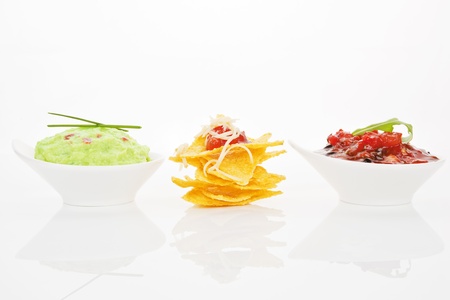 Delicious nachos with guacamole and tomato sauce in bowls isolated on white background.