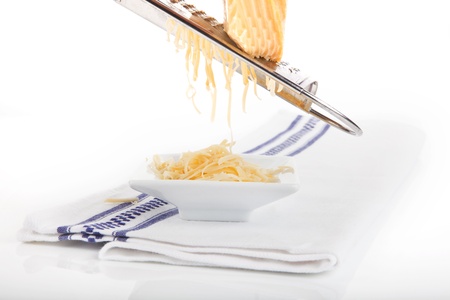 Grated cheese falling into white bowl on kitchen towel isolated on white background. の写真素材