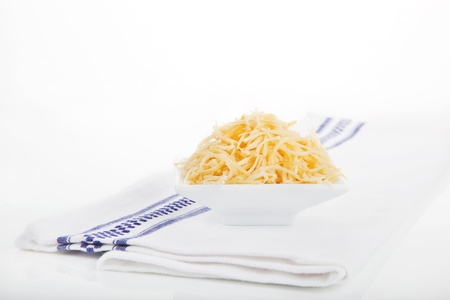 Shredded gouda cheese in white bowl on white towel isolated on white background. 