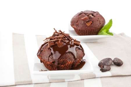 Delicious chocolate muffins with chocolate garnish and chocolate beans on kitchen cloth. Gourmet sweet food.の写真素材