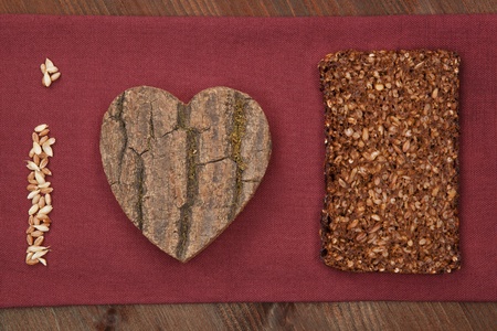 I love black bread made of dark bread slice, wooden heart and grain. Healthy lifestyle background.の写真素材