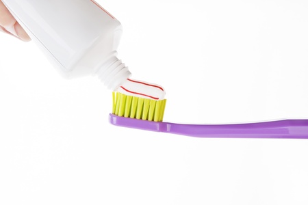 Red and white striped toothpaste on green and purple toothbrush isolated on white background. Dental...