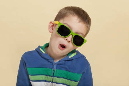 Funky cool young surprised boy with open mouth and yellow and green sunglasses. Youth fashion concept.の写真素材
