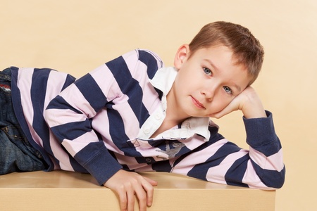 Young model boy lying on table and looking into camera. Youth fashion concept.の写真素材