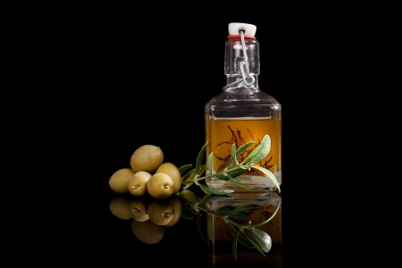 Delicious extra virgin olive oil with fresh olives and olive twig isolated on black background  Traditional culinary condiment の写真素材