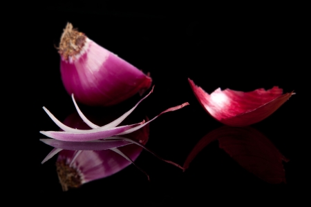 Purple onion slices  Skin and half onion in background isolated on black with reflection  Luxurious culinary still life の写真素材