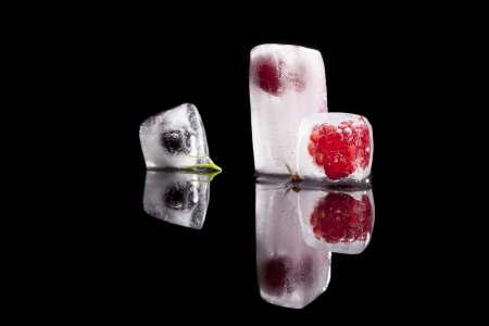 Fresh raspberry, cherry and blackcurrant frozen in ice blocks isolated on black background. Fresh summer concept.の写真素材