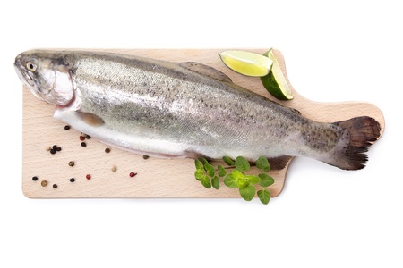 Fresh raw trout with pepper and fresh herbs on wooden cutting board isolated on white background, top view. Culinary seafood eating.の写真素材