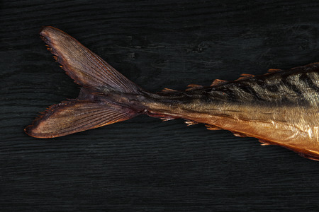 Smocked mackarel on dark wooden background top view. Culinary seafood eating. Fish tail background.の写真素材