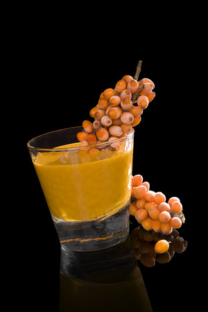 Sea buckthorn and sea buckthorn juice in glass isolated on black background. Healthy living, immune system booth.の写真素材