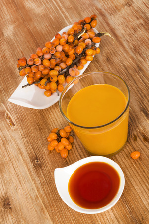 Sea buckthorn juice, oil and berries isolated on wooden background. Natural, healthy vitamin and detox.の写真素材