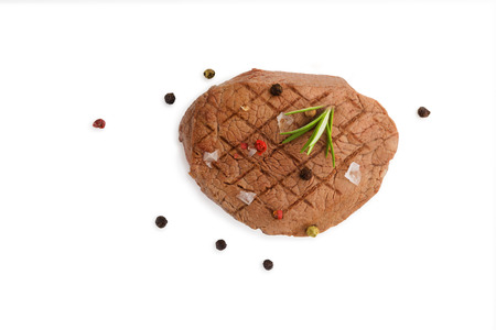 Grilled steak with fresh herb and colorful peppercorn isolated on white background, top view.の写真素材