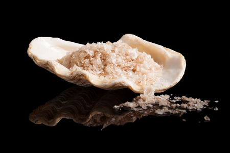 Himalaya salt crystals in beautiful seashell isolated on black background.の写真素材