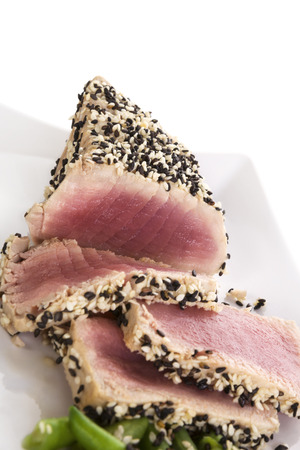 Tuna slices with white and black sesame seeds and lemon slices on white plate. Culinary seafood, healthy eating.の写真素材