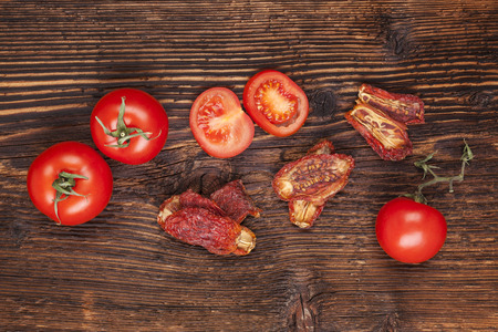 Delicious sundried and fresh tomatoes on brown wooden vintage textured background, top view. Traditional mediterranean kitchen.の写真素材