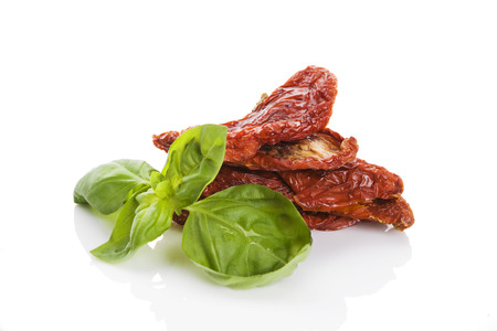 Sundried tomato with fresh basil herbs isolated on white backgroundの写真素材