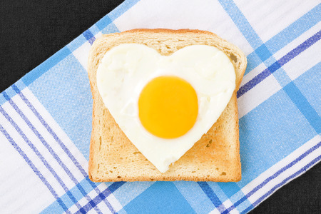 Sunny side up egg in heart shape on toast, top viewの写真素材