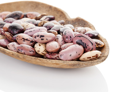 Dry pinto beans on old wooden scoop isolated on white background.  
