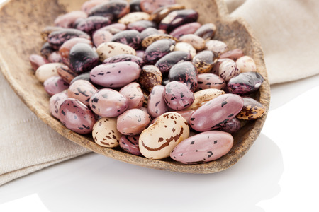 Pinto beans on wooden scoop on beige table cloth.  の写真素材