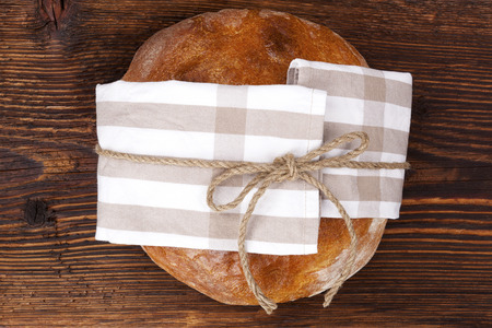 Delicious round bread loaf on wooden table, top view. Culinary bread eating.